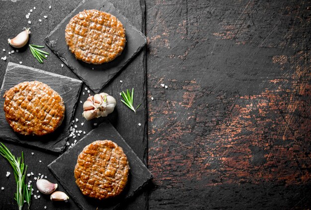 Cutlets on a black stone base with garlic and rosemary