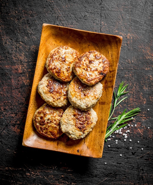 Cutlets on a wooden plate with rosemary