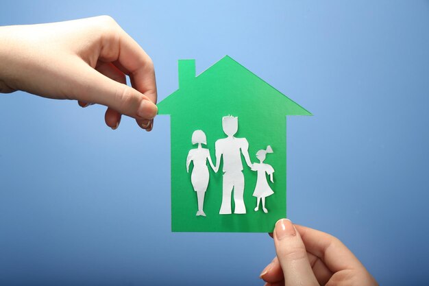 Photo cutout house with paper family in female hands on colorful background