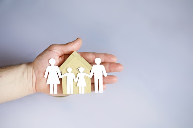 Cutout paper chain family with the protection of cupped hands, concept for security and care. Hands with cut out paper silhouette on table. Family care concept