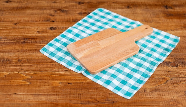 木製のテーブルのクローズアップの市松模様のナプキンのまな板
