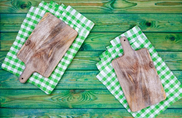 Cutting board over green checkered tablecloth, top view