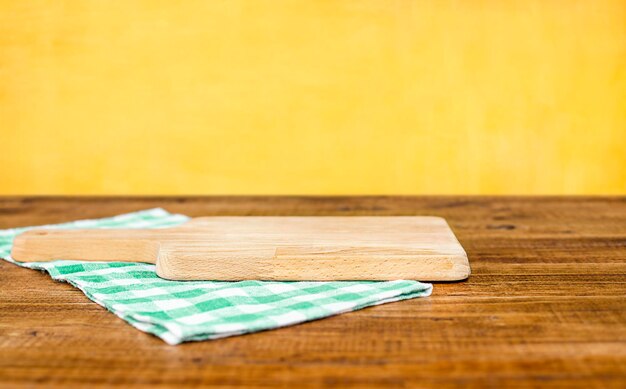 cutting board and napkin on wooden table against yellow wall