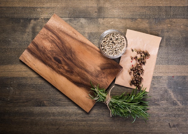 Cutting Board, rosemary and spices on a old wooden table
