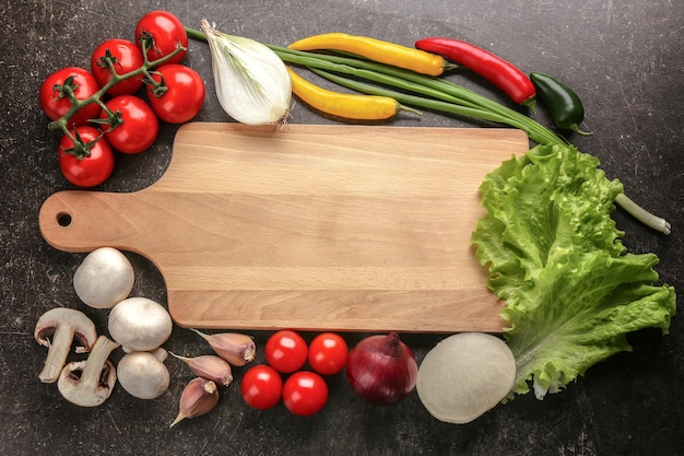 Cutting board and vegetables on gray background