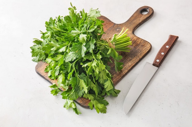 Cutting board with fresh parsley and knife on table