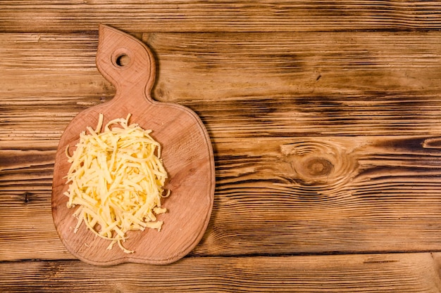 Cutting board with grated cheese on rustic wooden table Top view