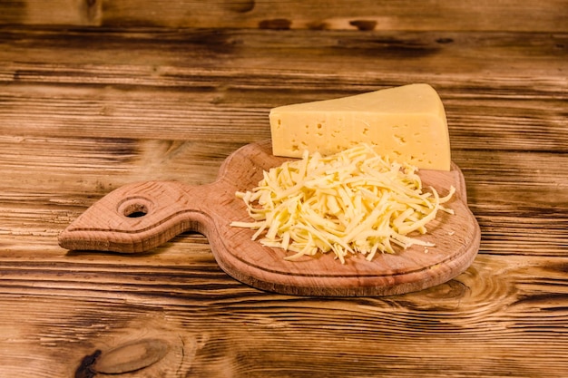 Cutting board with grated cheese on wooden table