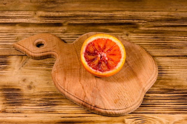 Cutting board with halved sicilian orange on rustic wooden table