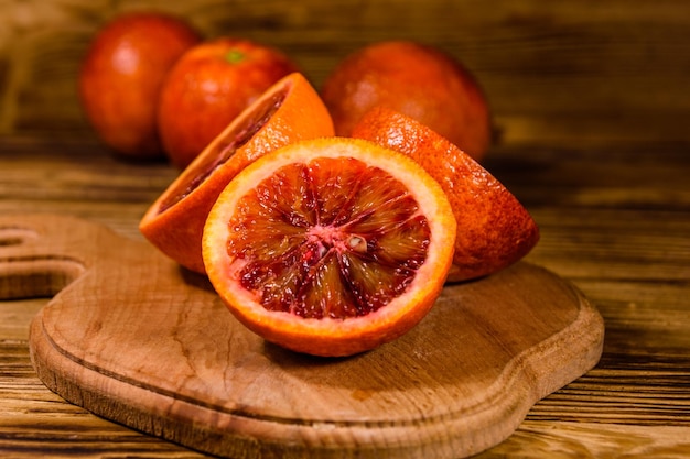 Cutting board with halved sicilian oranges on rustic wooden table