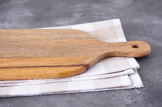 Cutting board with and kitchen towel on a gray background.