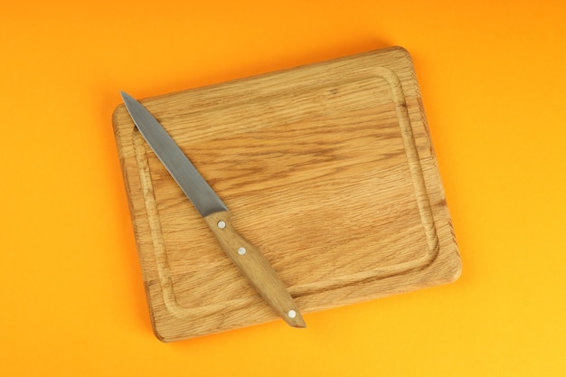 Cutting board with knife on orange background