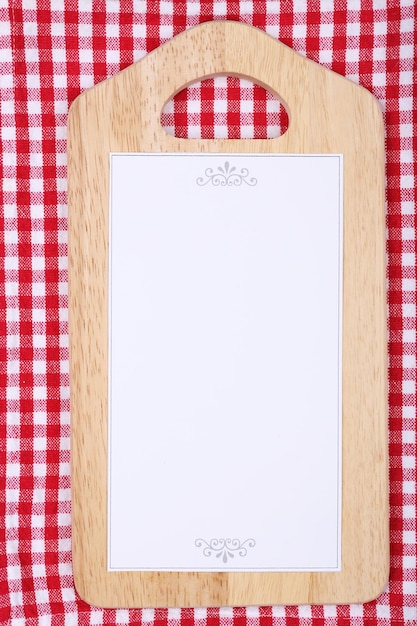Cutting board with menu sheet of paper on squared fabric background