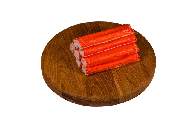 Cutting board with pile of crab sticks isolated on a white background