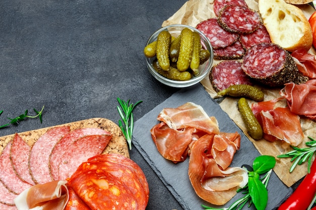 Cutting board with prosciutto, salami, bread and pickles