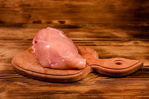 Cutting board with raw chicken fillet on rustic wooden table