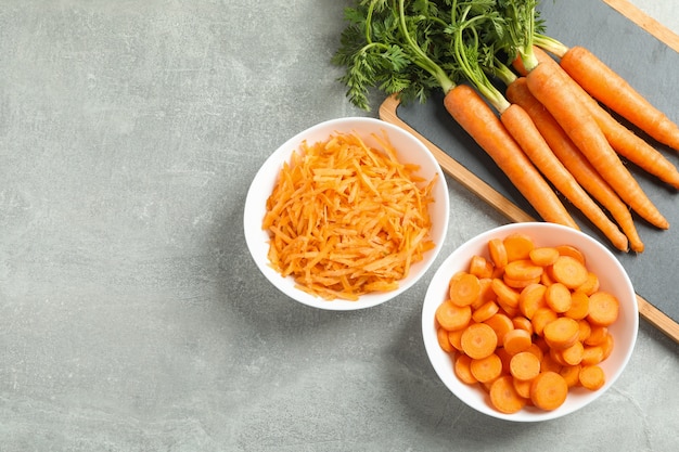 Cutting board with ripe carrots on grey table, space for text