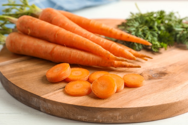 Cutting board with ripe carrots on wooden table