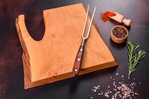 Cutting board with salt, spices and herbs on a dark concrete background. Cooking Healthy Food