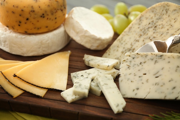 Cutting board with sliced assorted cheese on wooden background