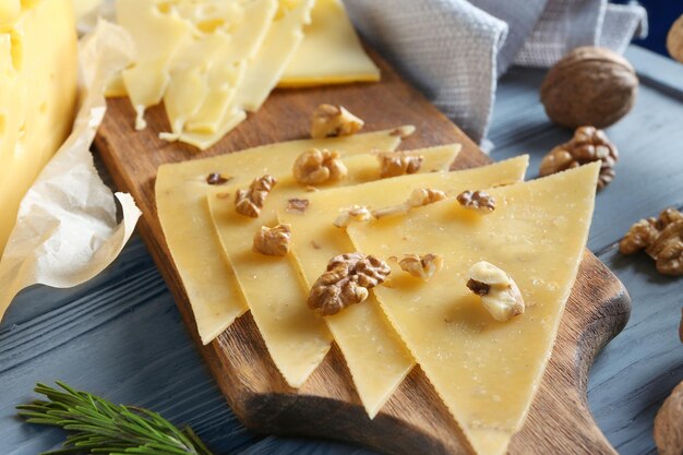 Разделочная доска с нарезанным сыром и грецкими орехами на деревянном столе