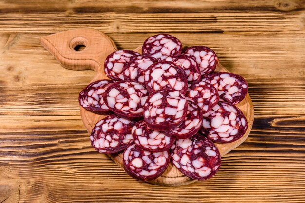 Cutting board with sliced salami sausage on rustic wooden table