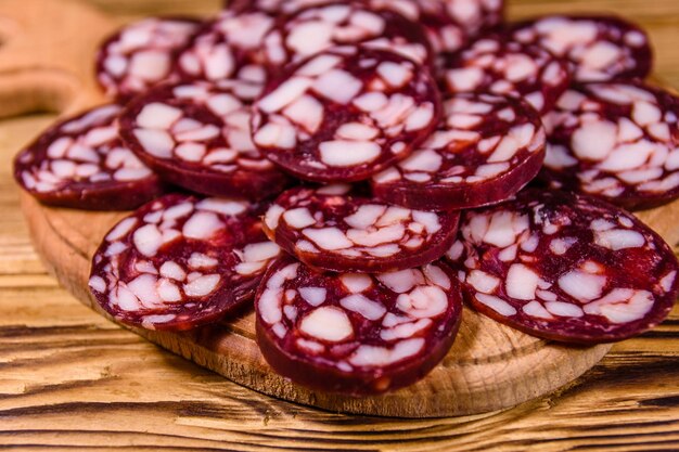 Cutting board with sliced salami sausage on rustic wooden table