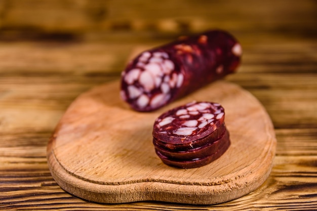 Cutting board with sliced salami sausage on rustic wooden table