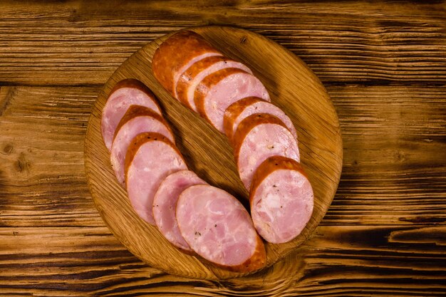 Cutting board with sliced sausage on rustic wooden table Top view