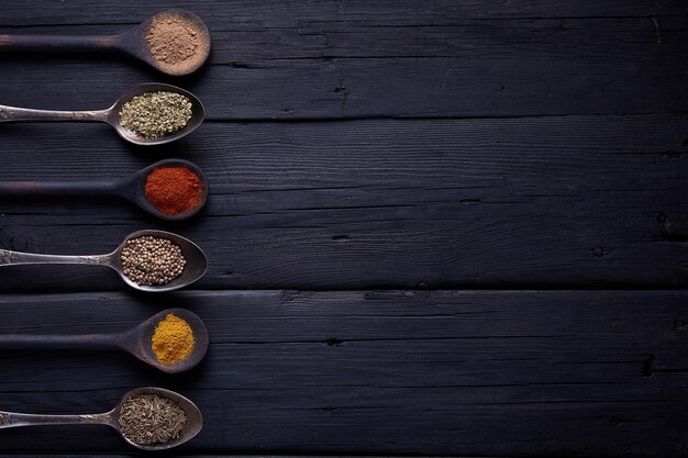 Cutting board with spices and herbs for cooking meat on dark background