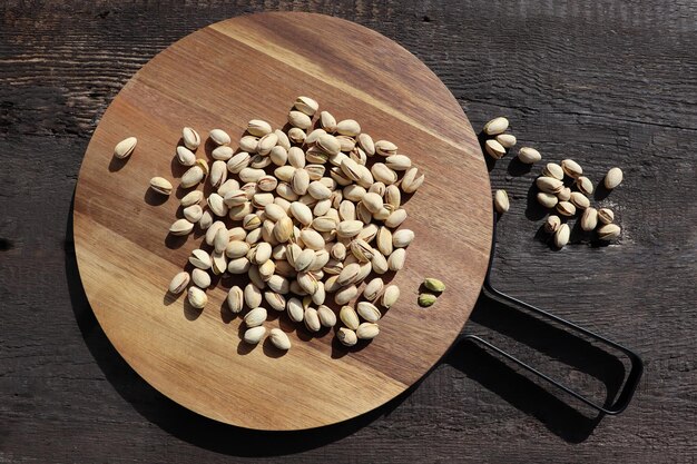 濃い田舎茶色の木製の背景に美味しいピスタチオナッツのカッティングボード