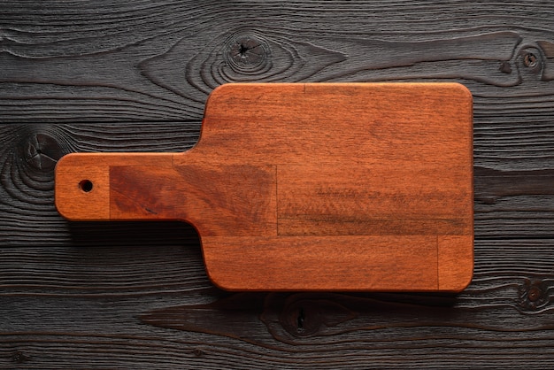 Cutting board on wooden wall top view