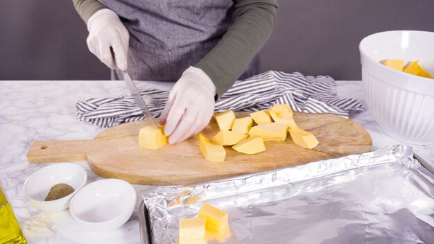 Cutting butternut squash on a wood cutting board.