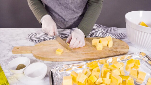 Cutting butternut squash on a wood cutting board.