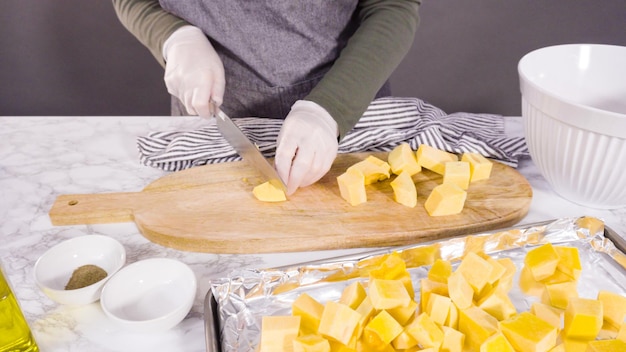 Cutting butternut squash on a wood cutting board.