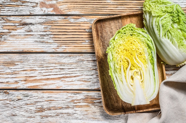 Cutting Chinese cabbage. Organic vegetables. White wooden background. Top view. Copy space.