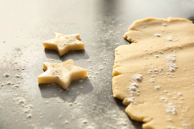 Cutting cookies from raw dough on table