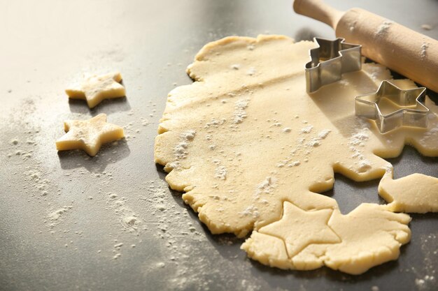 Cutting cookies from raw dough on table