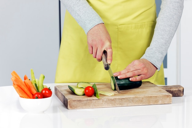 Cutting cucumber and vegetables on background