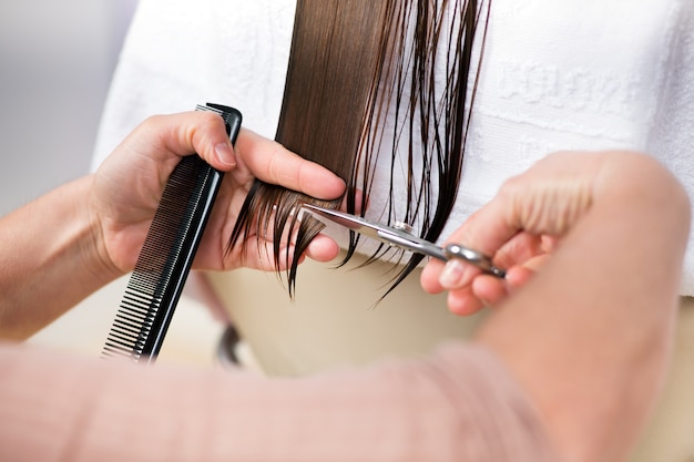 Cutting ends of long brown hair in close-up