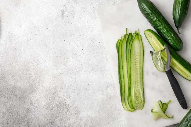 Cutting fresh cucumber on a chop board Sliced cucumber on marble board top view copy space