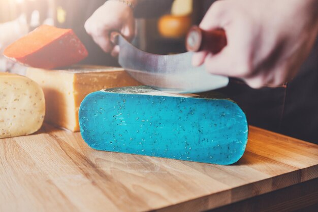 Cutting gouda pesto lavender, blue cheese in grocery shop, closeup