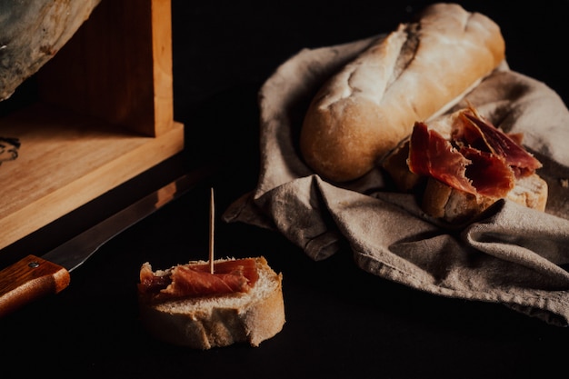 Cutting Iberian Ham with bread, wood, knife.