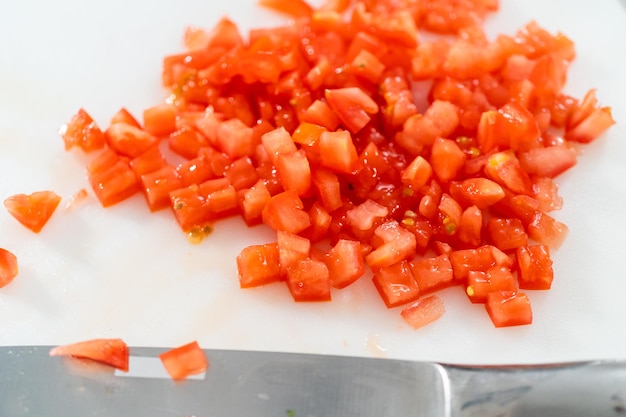 Cutting ingredients on a white cutting board to make classic guacamole dip.