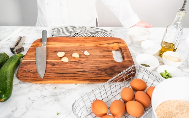 Cutting ingredients on a wood cutting board to make zucchini cakes.