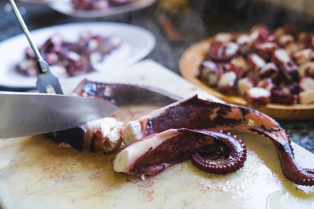 Foto polpo di taglio con coltello sul tavolo della cucina. concetto di pesce.