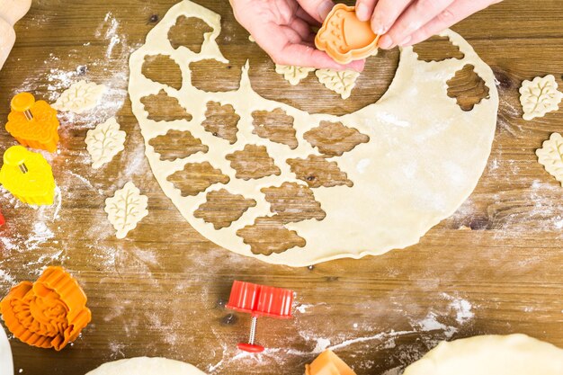 Cutting out Autumn leafs with cookie stamper to decorate pumpkin pie.