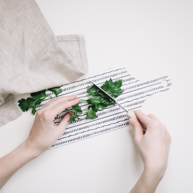Photo cutting parsley for salad top view image of female hands with knife slicing greenery on a wooden boa...