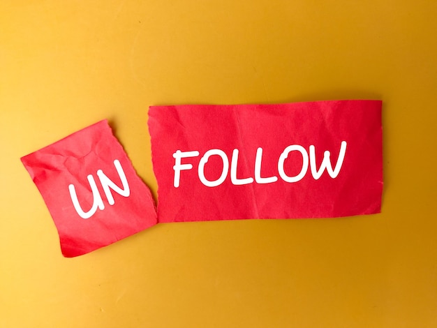 写真 「unfollow」と書かれた赤い紙を切る