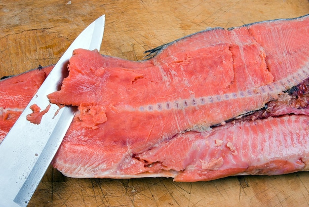 Foto tagliare il salmone con un coltello